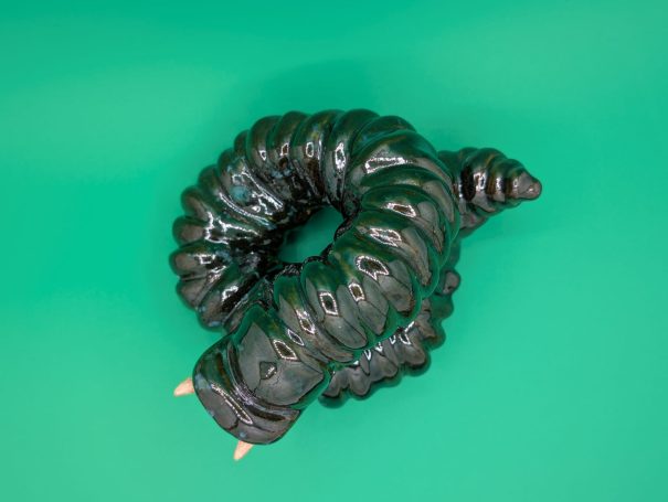 A shiny coiled serpent like sculpture with protruding teeth