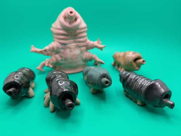 Small ceramic sculptures.  A pink standing tardigrade 'shepherds' five smaller creatures 