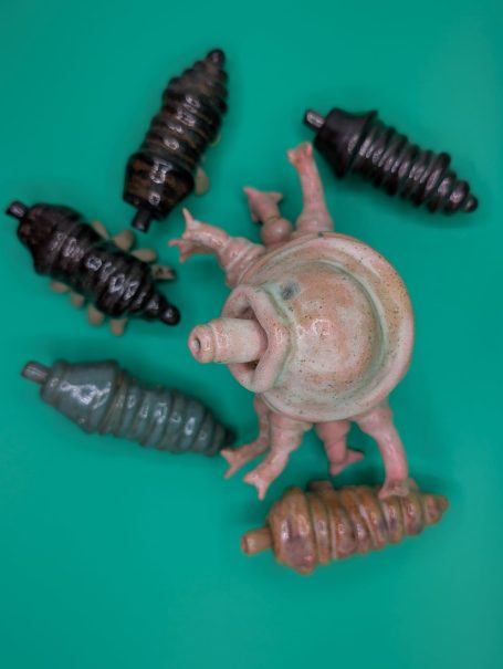 Small ceramic sculptures.  A pink standing tardigrade 'shepherds' five smaller creatures 