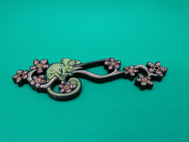 A wooden charm of a chameleon on a flowering branch