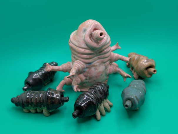 Small ceramic sculptures.  A pink standing tardigrade 'shepherds' five smaller creatures 