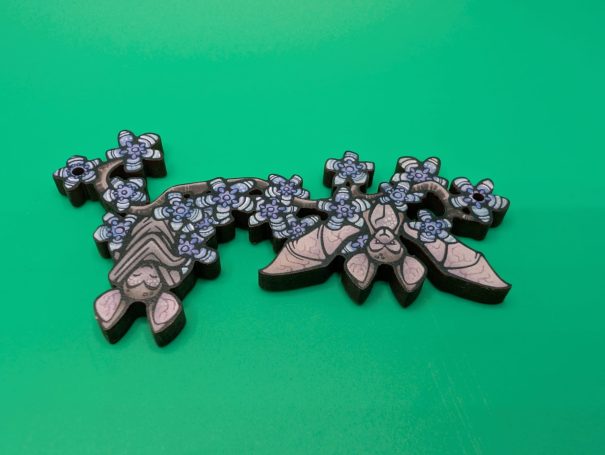 A wooden charm of bats hanging from a flowering branch