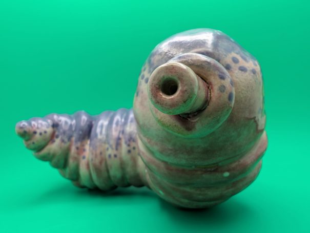 Ceramic sculpture - a fat worm-like creature with proboscosis.  A speckled purple patterning over it's ribbed body