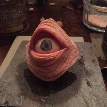 Polymer clay eye sitting on a stone tile