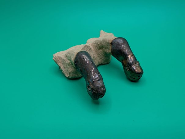 A partial sculpture showing two fingers with a blackened metallic glaze