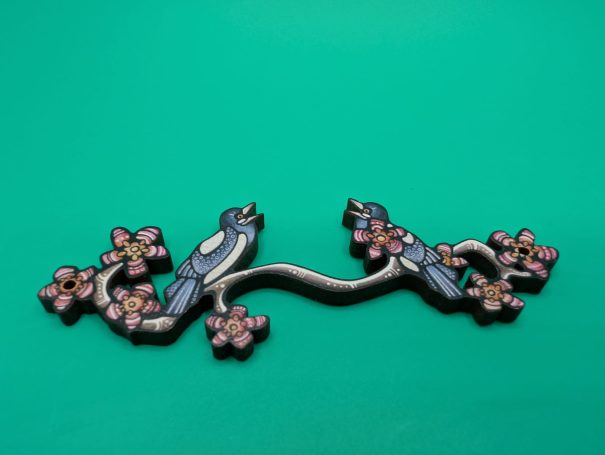A wooden charm of two magpies on a flowering branch