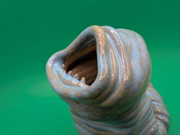 Ceramic sculpture - An eyeless thin coiled worm creature wailing with a large open toothy mouth